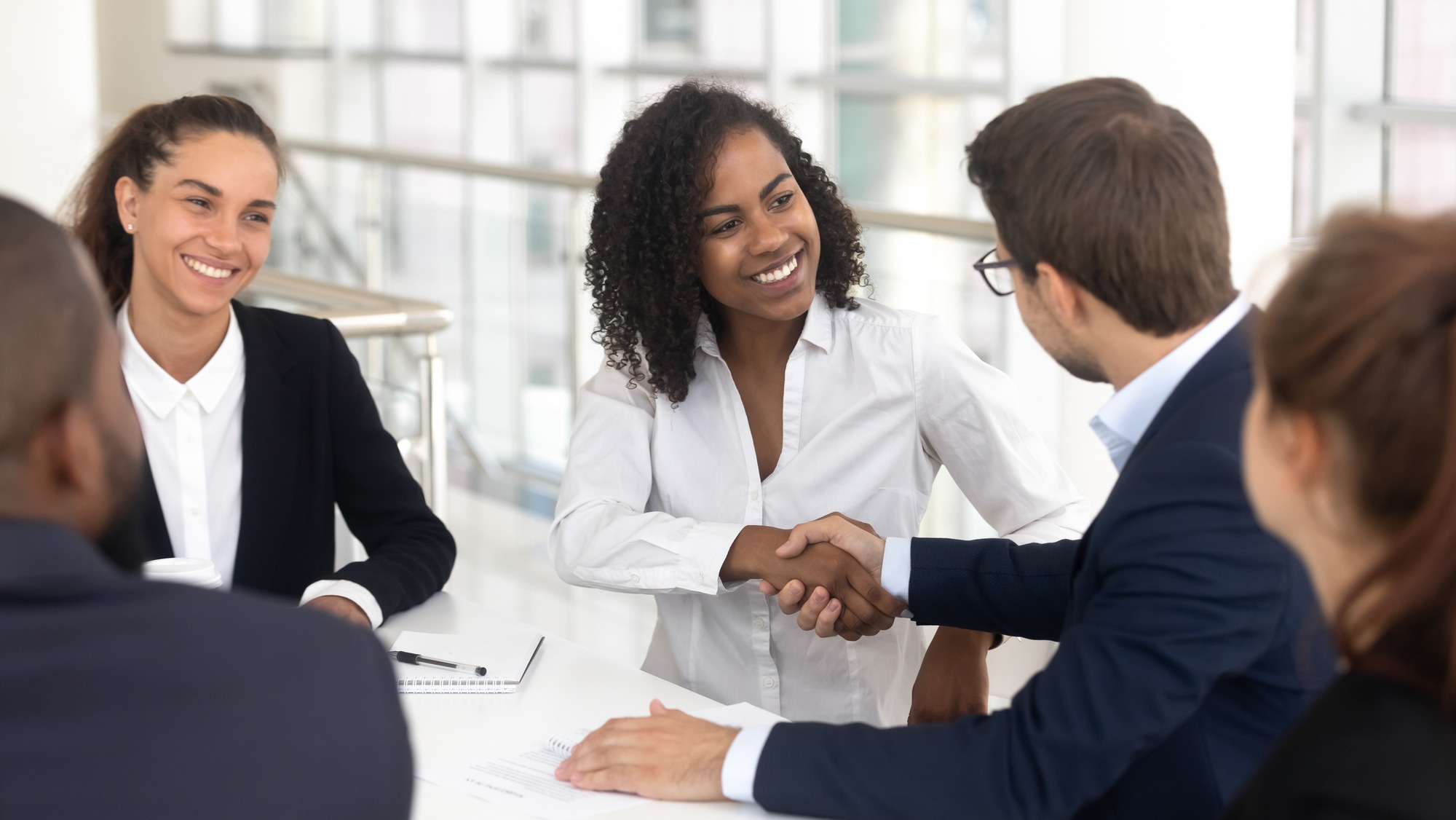 Multiracial businessman businesswoman shake hands starting collaboration at group negotiations